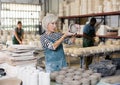 Mature woman ceramist arranging new bowls in workshop