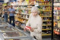 Mature woman choosing frozen food in supermarket. Young woman purchasing goods in grocery store