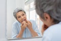 Mature woman cleaning teeth with floss