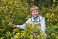 The mature woman costs among the blossoming bushes of a trailing