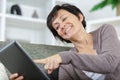 mature woman on couch using digital tablet