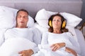 Woman Covering Her Ears With Headphones While Man Snoring Royalty Free Stock Photo