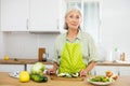 Mature woman cutting fresh vegetables for dinner Royalty Free Stock Photo