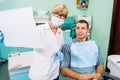 Mature woman dentist looks at teeth x-rays. Discussion of issues. Cropped shot of professional dentist showing jaw and teeth with