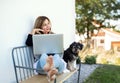 Mature woman with dog working in home office outdoors on bench, using laptop. Royalty Free Stock Photo