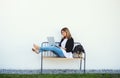 Mature woman with dog working in home office outdoors on bench, using laptop. Royalty Free Stock Photo