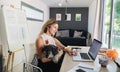 Mature woman with dog working indoors in home office in container house in backyard. Royalty Free Stock Photo