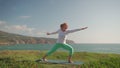 Fit senior woman practicing warrior pose Virabhadrasana on beach