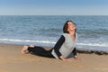 Mature woman doing yoga cobra on the beach