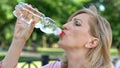 Mature woman drinking water from bottle in park, maintaining water balance Royalty Free Stock Photo