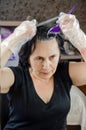 Mature woman dying her hair in front of mirror. woman with brush for hair-dye coloring her hair