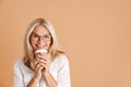 Mature woman in eyeglasses smiling while drinking coffee Royalty Free Stock Photo