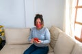 A mature woman with a face mask sitting in the living room using a cell phone Royalty Free Stock Photo