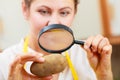 Woman inspecting potato with magnifying glass. Royalty Free Stock Photo