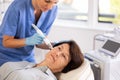 Mature woman getting facial deep hydration procedure from experienced cosmetologist in aesthetic medicine office