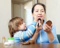 Mature woman with granddaughter puts facepowder