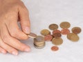 Mature, woman hand putting coins into a pile, heap, on white tablecloth background. Close. European euro coins, counting
