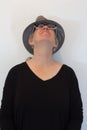 Mature woman in hat, head tilted back, eyes closed, neutral background Royalty Free Stock Photo