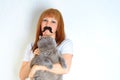 Mature woman having fun with a fake moustache and embracing pet.