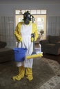Mature woman in Haz Mat suit with blue bucket and mop
