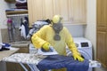 Mature woman in Haz Mat suit ironing shirt on board with steam Royalty Free Stock Photo