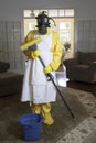 Mature woman in Haz Mat suit in living room with mop