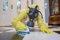 Mature woman in Haz Mat suit scrubbing floor with brush