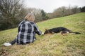 Mature woman sitting outdoors with an Alsatian puppy