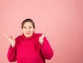 A mature woman in her early fifties with a pink turtleneck looking at the camera exasperated with hands in the air Royalty Free Stock Photo