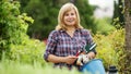 mature woman holding horticultural tools in garden