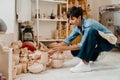 Mature woman holding handcrafts while sitting at the workshop