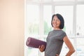 Mature woman holding rolled up exercise mat at gym