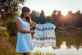 Mature woman holding traditional Ukrainian towel with embroidery in front of river in autumn park.