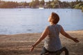 Mature woman at holiday destination beach contemplating lake sitting on shore Royalty Free Stock Photo