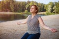 Mature woman at holiday destination beach contemplating lake sitting on shore Royalty Free Stock Photo