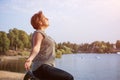 Mature woman at holiday destination beach contemplating lake sitting on shore Royalty Free Stock Photo