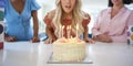 Mature Woman At Home Celebrating Birthday With Friends And Blowing Out Candles On Cake Royalty Free Stock Photo