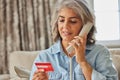 Mature Woman At Home Giving Credit Card Details On The Phone Royalty Free Stock Photo