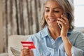 Mature Woman At Home Giving Credit Card Details On The Phone Royalty Free Stock Photo