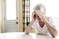 Mature woman at home touching her head with her hands while having a headache pain Royalty Free Stock Photo