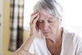 Mature woman at home touching her head with her hands while having a headache pain Royalty Free Stock Photo