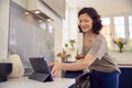 Mature Woman In Kitchen At Home Cooking Meal Following Recipe On Digital Tablet