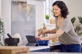 Mature Woman In Kitchen At Home Cooking Meal Following Recipe On Digital Tablet