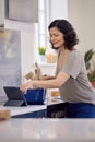 Mature Woman In Kitchen At Home Cooking Meal Following Recipe On Digital Tablet