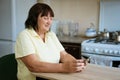 Mature woman in the kitchen at the table with the phone Royalty Free Stock Photo