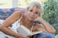 Mature woman is lying and reading book on a couch Royalty Free Stock Photo