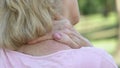 Mature woman massaging numb neck and shoulders, spine injury consequences