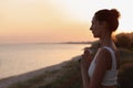 Mature woman meditating near sea in evening. Space for text Royalty Free Stock Photo