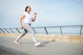 Mature woman performing morning jog on the city bridge. Active people and sport concept