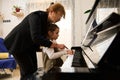 Mature woman pianist teacher giving piano lesson to a little school girl, teaching the position of fingers on piano keys Royalty Free Stock Photo